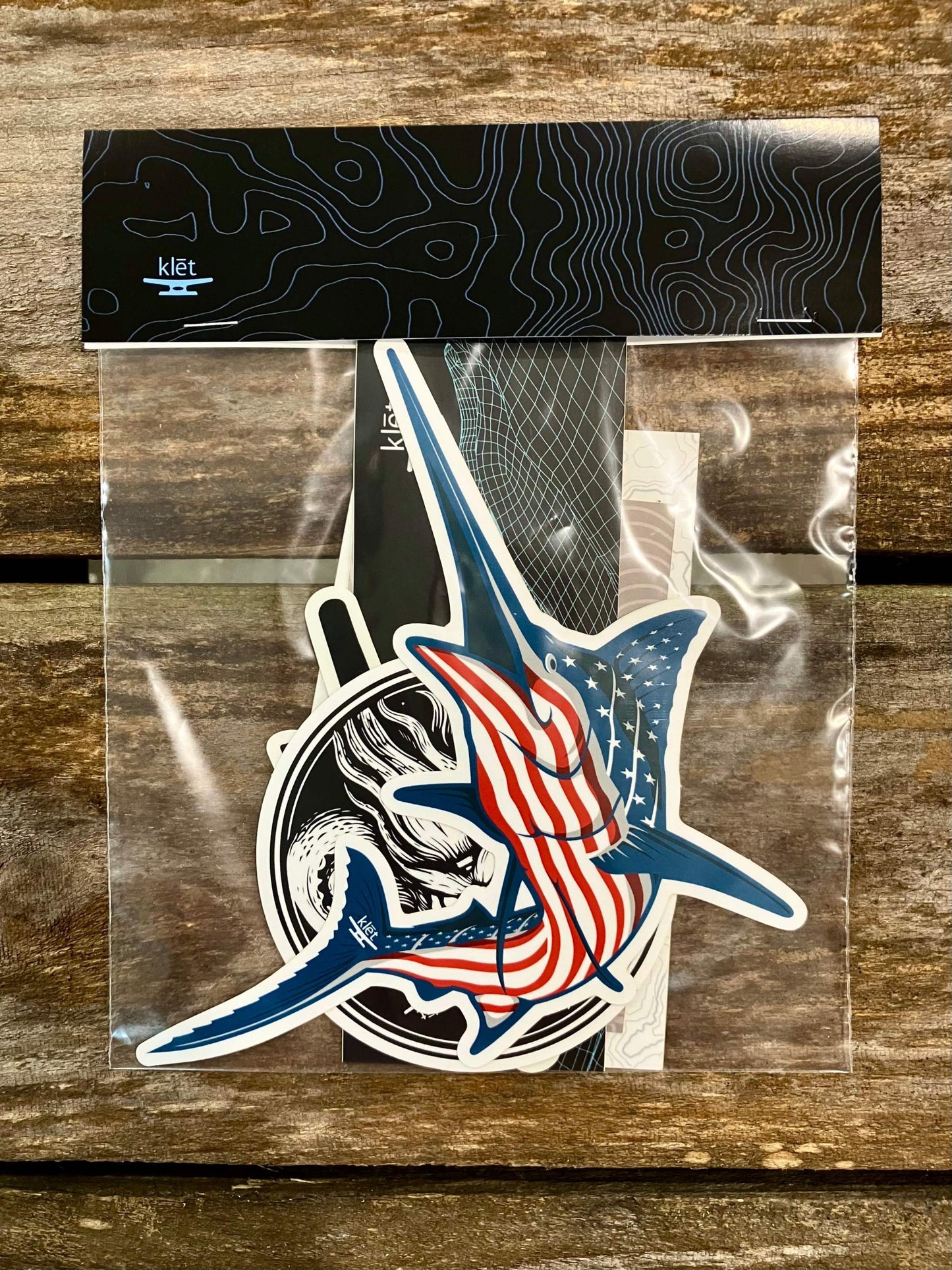 Klēt Sticker Pack with 7 assorted designs featuring patriotic and marine-themed graphics in a clear plastic packaging with black top label.