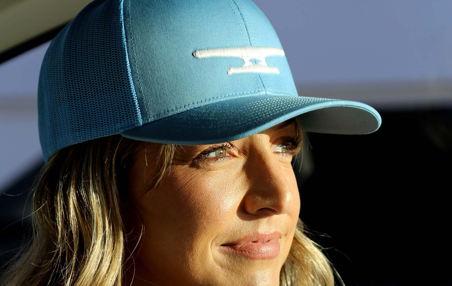 Woman wearing a light blue Klēt cap with white puff embroidered monogram logo