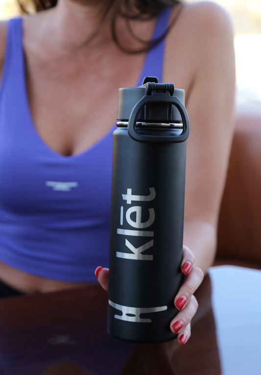 Klēt Drifter Travel Water Bottle black stainless steel insulated leak-proof design held by woman in purple top