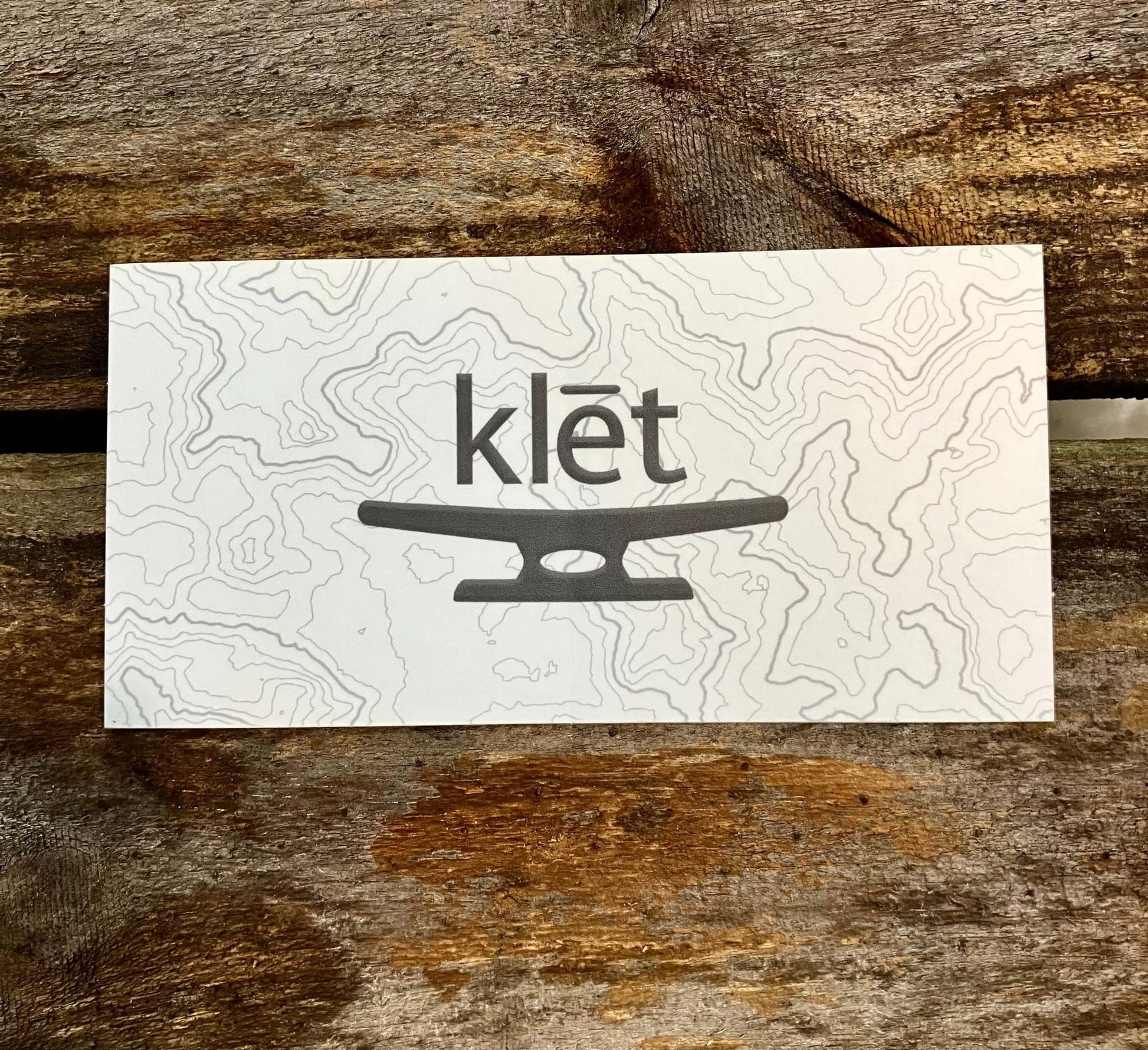Klēt TopoMap 5 inch sticker with contour map design on wooden background Klēt - TopoMap Sticker
