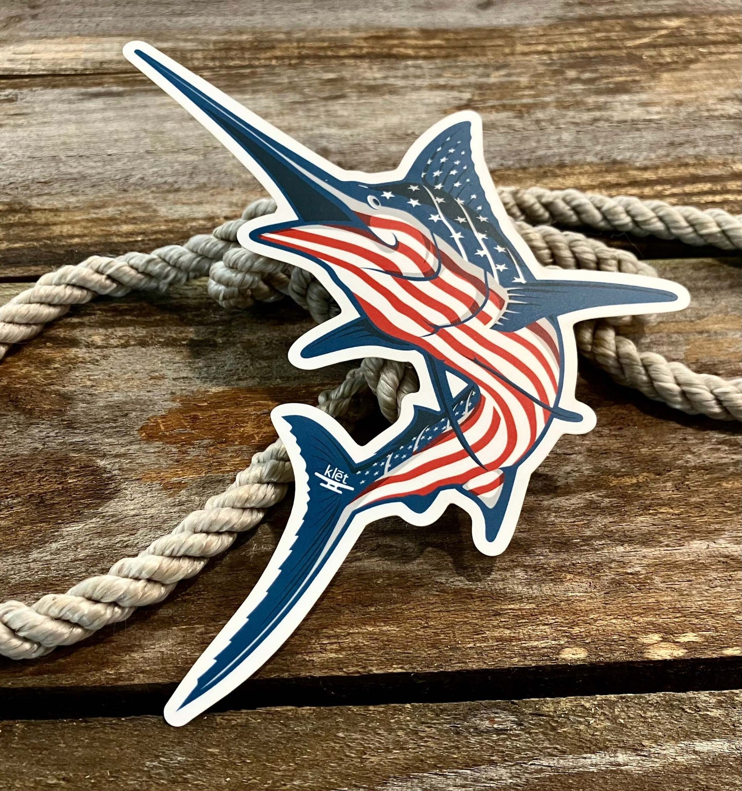 Klēt America Stripe Marlin Sticker 8-inch with American flag design on a wooden surface with rope background